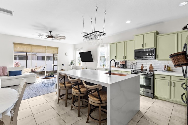 kitchen featuring a kitchen island with sink, sink, green cabinetry, and appliances with stainless steel finishes