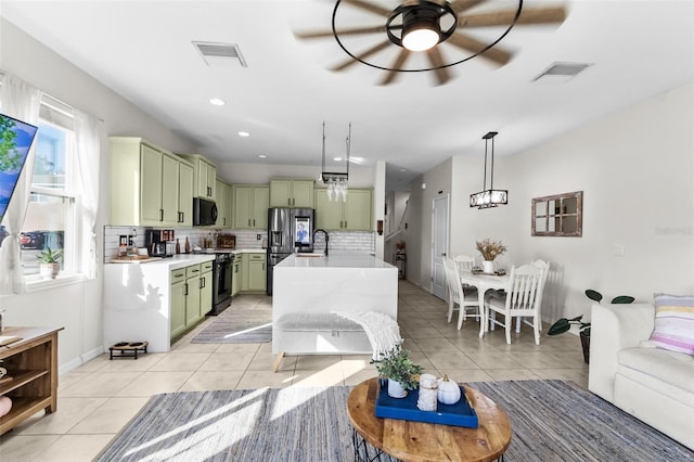 kitchen featuring green cabinets, a healthy amount of sunlight, hanging light fixtures, and black appliances