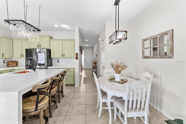 kitchen featuring decorative backsplash, stainless steel fridge, decorative light fixtures, and green cabinetry