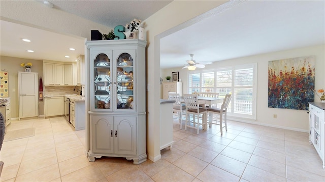 kitchen featuring backsplash, ceiling fan, sink, and light tile patterned floors