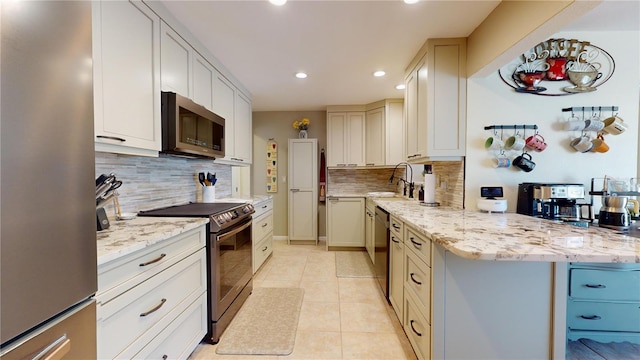 kitchen with light stone countertops, sink, stainless steel appliances, backsplash, and light tile patterned floors