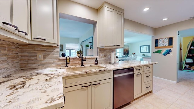 kitchen with stainless steel dishwasher, plenty of natural light, light stone counters, and cream cabinetry