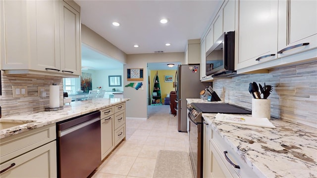 kitchen with backsplash, light stone counters, light tile patterned floors, and stainless steel appliances