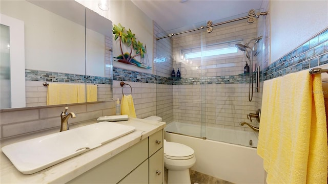 full bathroom with combined bath / shower with glass door, vanity, toilet, and tile walls