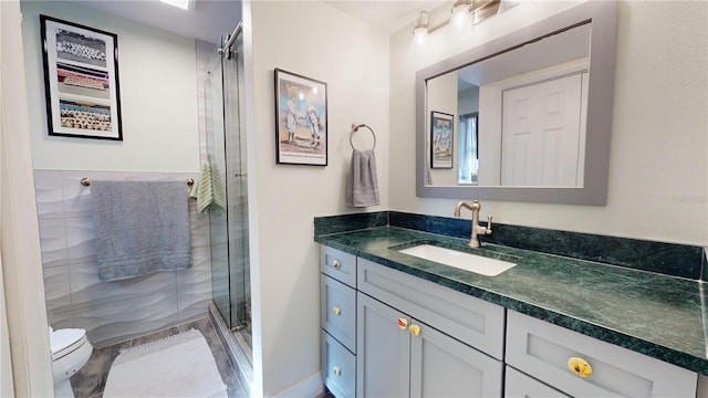 bathroom with vanity, toilet, and a shower with door