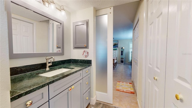 bathroom with a textured ceiling, vanity, and tile patterned floors