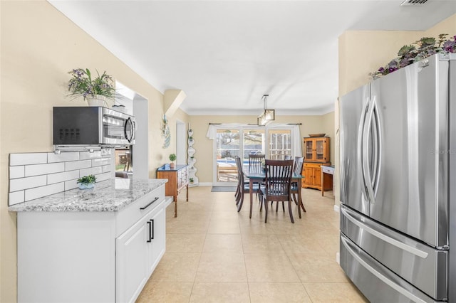 kitchen with backsplash, light stone countertops, light tile patterned flooring, white cabinetry, and stainless steel appliances