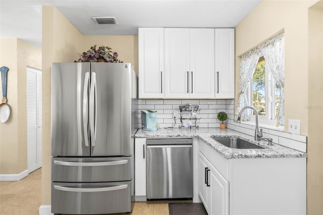 kitchen featuring light stone counters, stainless steel appliances, sink, light tile patterned floors, and white cabinets