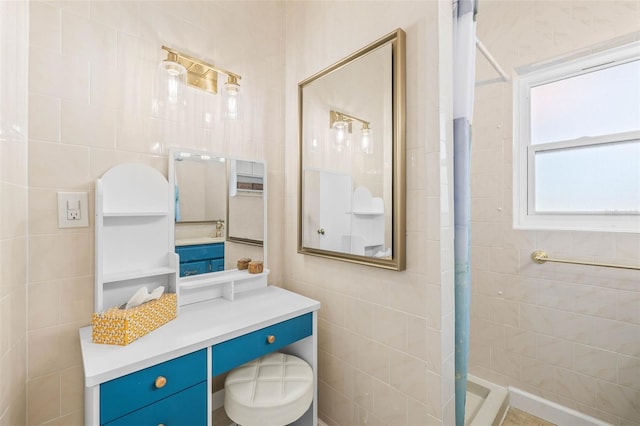 bathroom featuring a shower, vanity, and tile walls