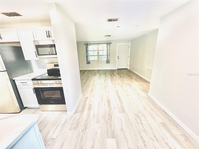 kitchen with white cabinets, light hardwood / wood-style floors, light stone counters, and appliances with stainless steel finishes