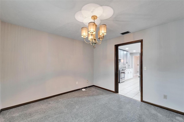 carpeted spare room featuring a notable chandelier