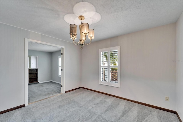 empty room featuring a textured ceiling, carpet floors, and an inviting chandelier