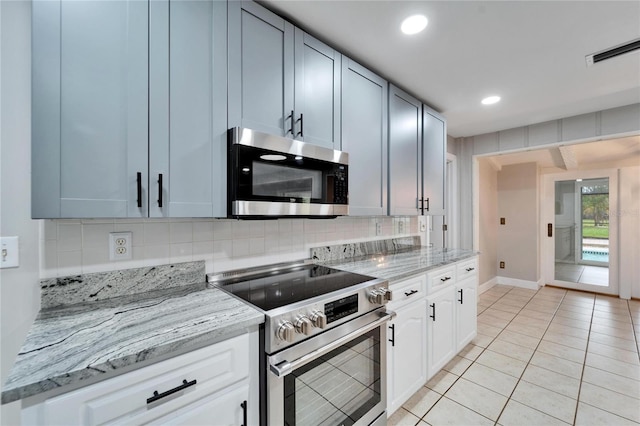 kitchen with stainless steel appliances, white cabinets, light stone counters, backsplash, and light tile patterned flooring