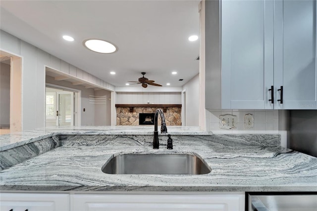 kitchen featuring decorative backsplash, white cabinetry, sink, and light stone countertops