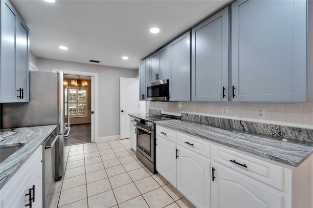 kitchen with white cabinets, light stone counters, light tile patterned floors, and appliances with stainless steel finishes