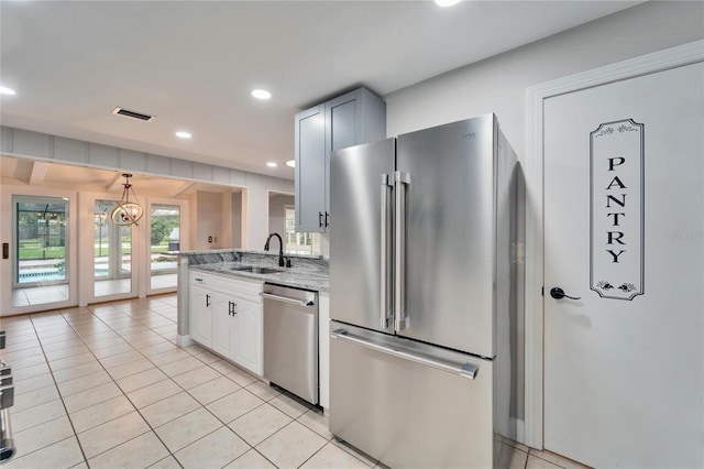 kitchen with white cabinets, sink, light tile patterned floors, light stone counters, and stainless steel appliances