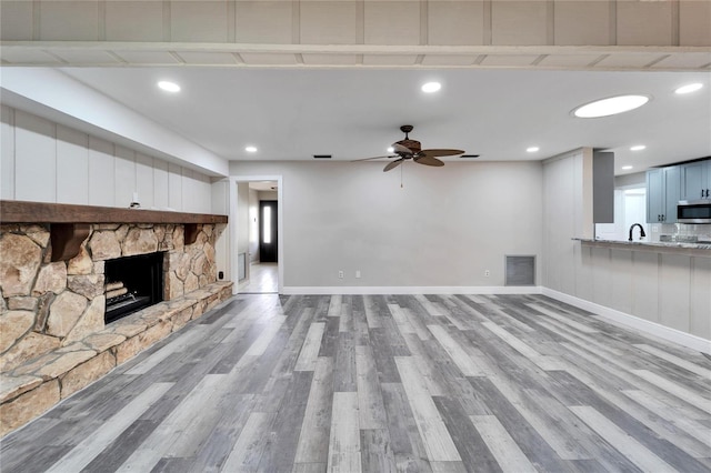 unfurnished living room featuring ceiling fan, a fireplace, and light hardwood / wood-style flooring