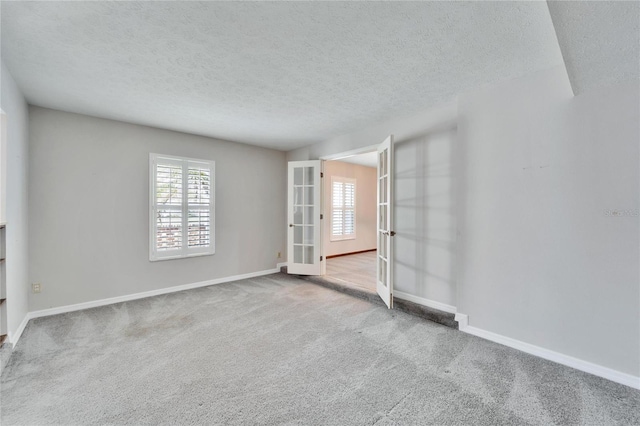 carpeted empty room featuring french doors and a textured ceiling