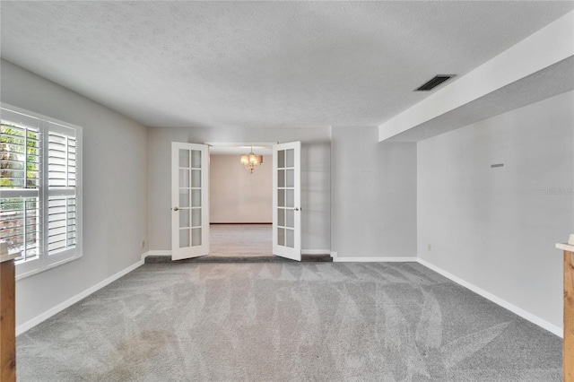 carpeted spare room featuring french doors and a textured ceiling