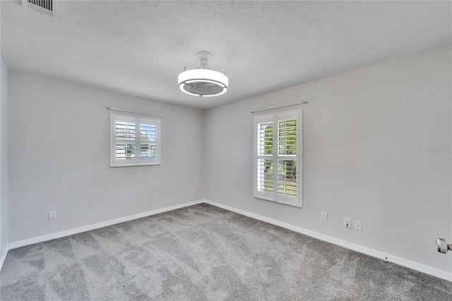 carpeted empty room with a textured ceiling