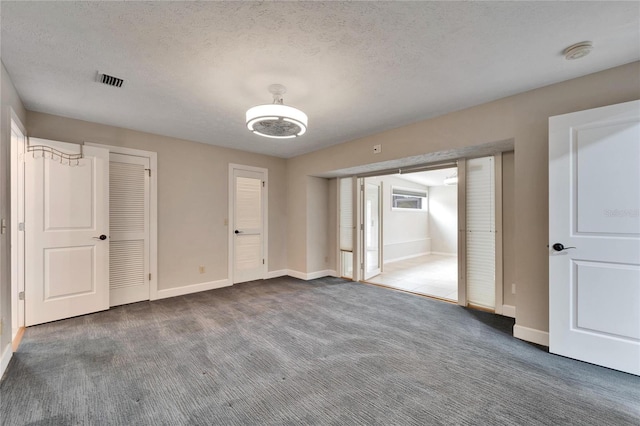 unfurnished bedroom featuring dark carpet and a textured ceiling