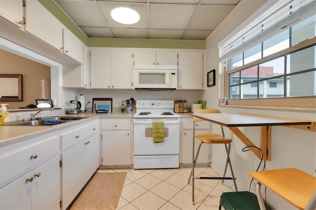 kitchen with sink, backsplash, white cabinets, and white appliances