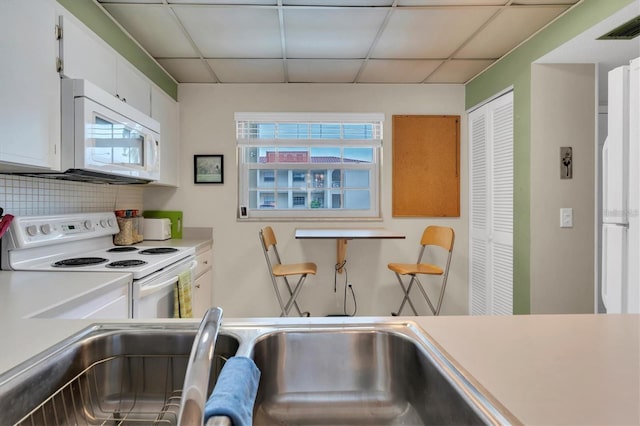 kitchen with sink, white cabinetry, white appliances, decorative backsplash, and a drop ceiling