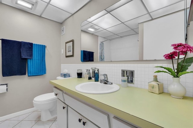 bathroom with a paneled ceiling, decorative backsplash, vanity, toilet, and tile patterned floors