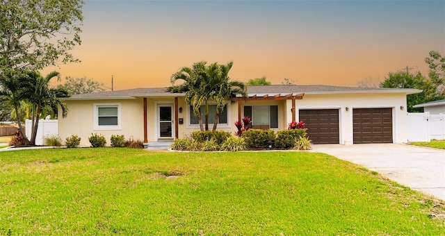 ranch-style home featuring a garage and a yard