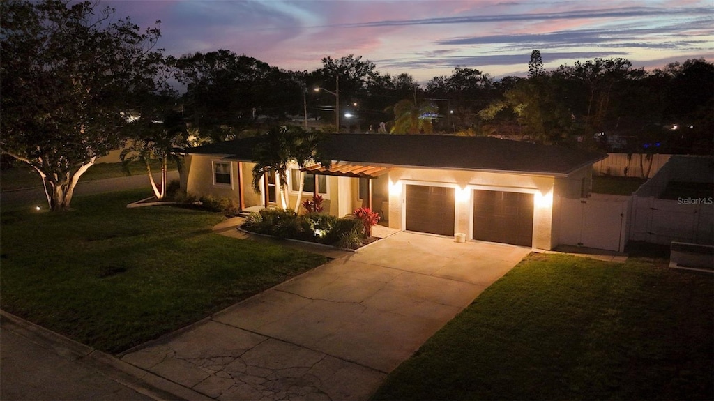 ranch-style home featuring a garage and a lawn