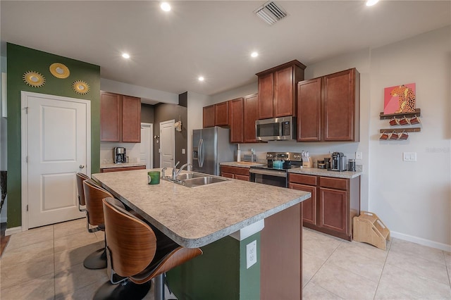 kitchen featuring sink, stainless steel appliances, a breakfast bar area, and an island with sink