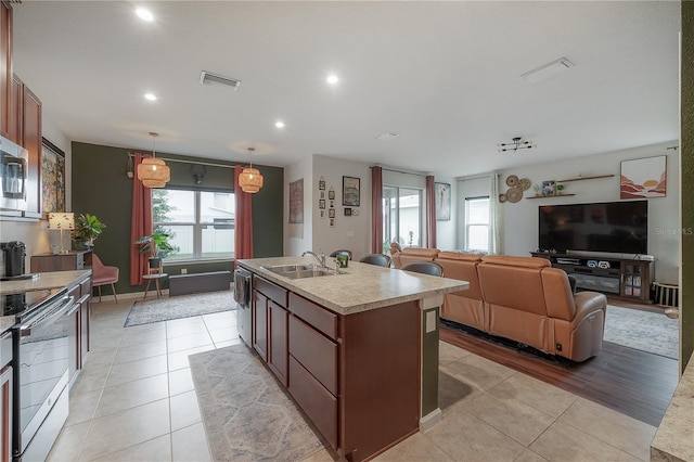 kitchen featuring hanging light fixtures, sink, an island with sink, appliances with stainless steel finishes, and light tile patterned flooring