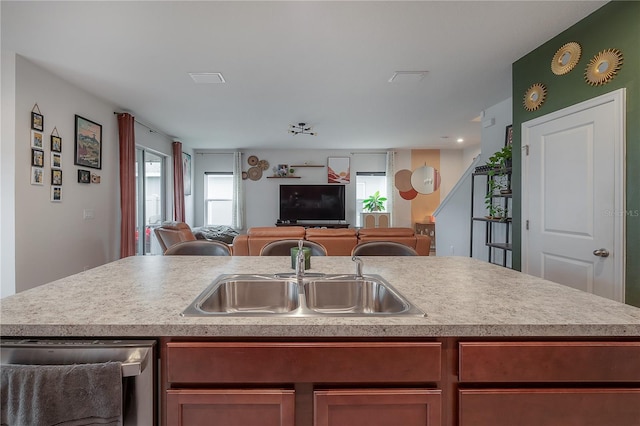 kitchen featuring dishwasher, sink, an island with sink, and a wealth of natural light