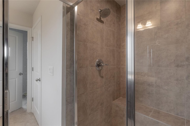 bathroom with a shower with door and tile patterned flooring