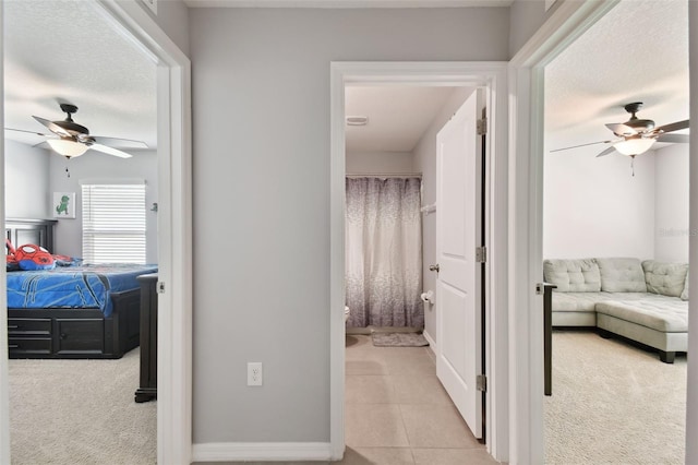 hall with light colored carpet and a textured ceiling