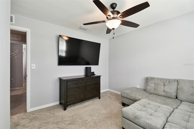 carpeted living room featuring ceiling fan and a textured ceiling