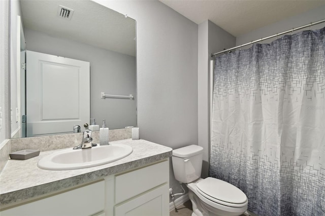 bathroom with a textured ceiling, vanity, toilet, and curtained shower