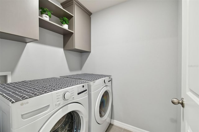 clothes washing area featuring cabinets, washing machine and dryer, and light tile patterned floors