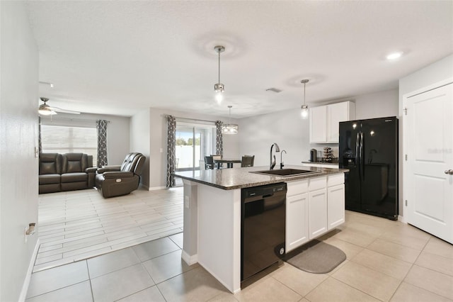 kitchen featuring decorative light fixtures, a center island with sink, white cabinetry, and black appliances