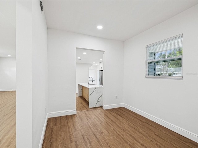 unfurnished room featuring sink and light hardwood / wood-style flooring