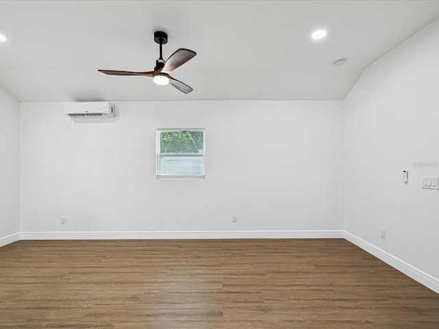 spare room featuring hardwood / wood-style floors, a wall unit AC, and ceiling fan