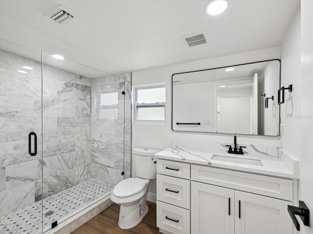 bathroom with wood-type flooring, walk in shower, vanity, and toilet