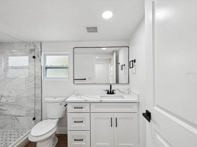 bathroom with tiled shower, vanity, and toilet