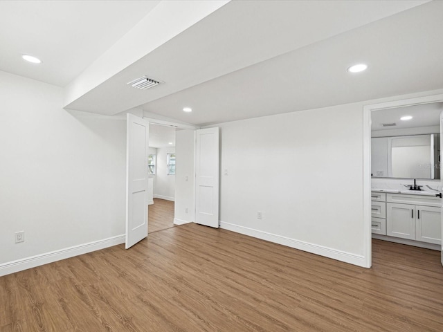 basement featuring sink and light wood-type flooring