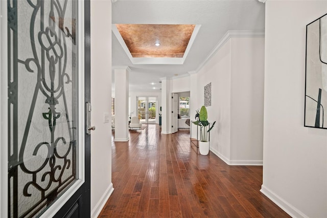 foyer featuring a raised ceiling, ornate columns, dark hardwood / wood-style flooring, and ornamental molding