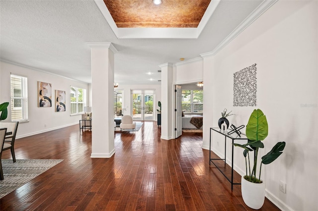 entrance foyer featuring a raised ceiling, ornate columns, crown molding, and dark hardwood / wood-style floors