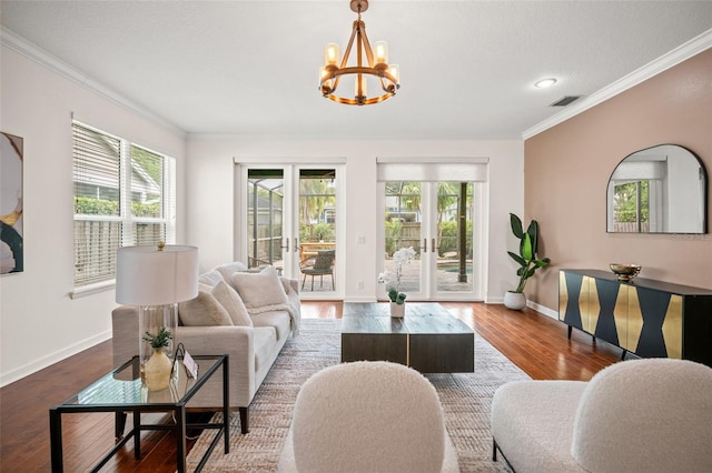 living room with french doors, hardwood / wood-style flooring, crown molding, and a notable chandelier