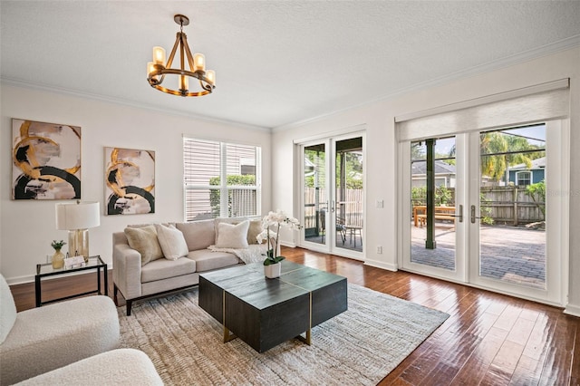 living room featuring french doors, an inviting chandelier, dark hardwood / wood-style flooring, a textured ceiling, and ornamental molding