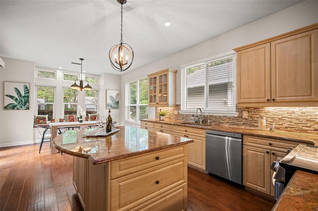 kitchen with light brown cabinets, sink, stainless steel dishwasher, decorative light fixtures, and a kitchen island