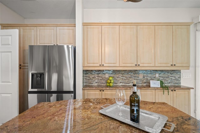 kitchen featuring backsplash, stainless steel fridge with ice dispenser, light brown cabinetry, and dark stone counters